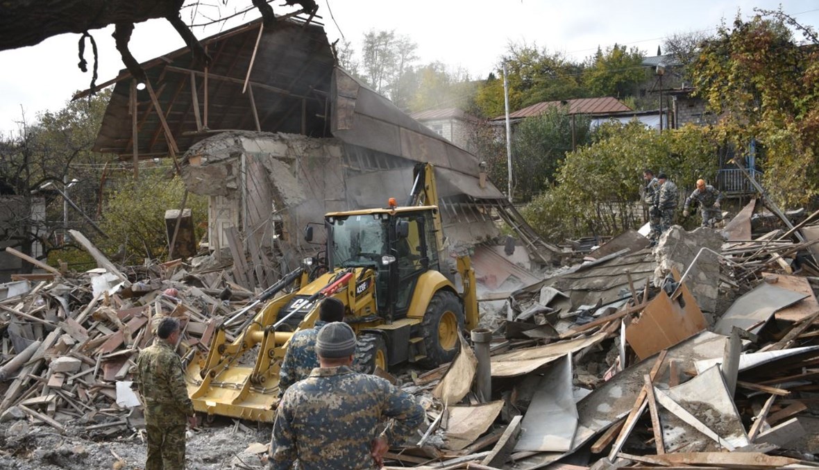 عمال إنقاذ يبحثون في ركام منزل مدمر في ستيباناكيرت، عاصمة إقليم ناغورنو- كراباخ (6 ت2 2020، أ ف ب). 