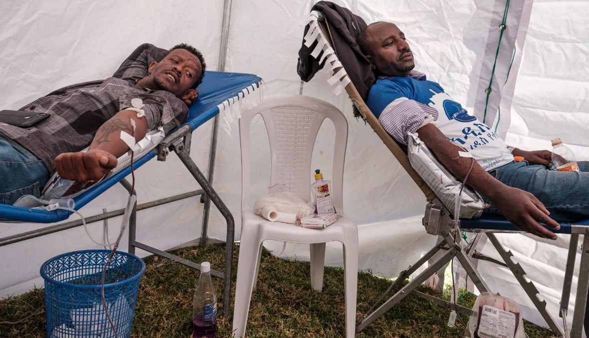رجلان يترعان بالدم في اطار حملة نظتمها إدارة مدينة أديس أبابا، في أديس أبابا (12 ت2 2020، أ ف ب). 
