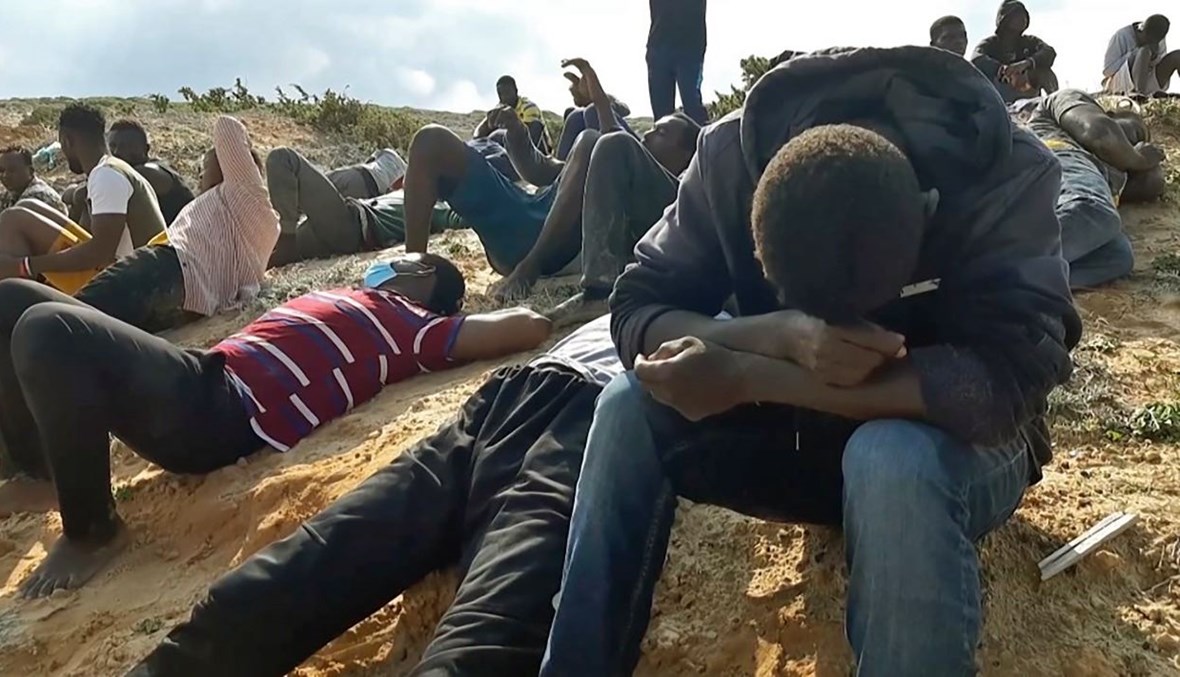 مهاجرون يستريحون على شاطئ في الخمس غرب طرابلس، بعد إنقاذهم (12 ت2 2020، أ ف ب). 