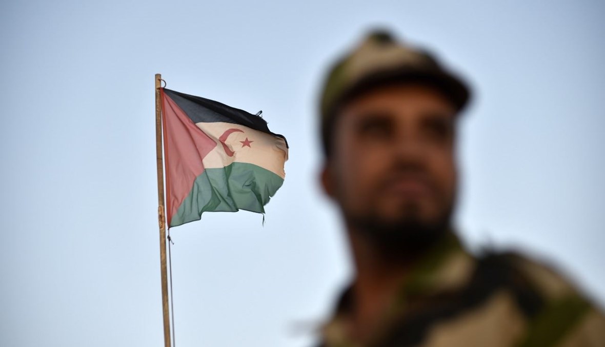 جندي من جبهة البوليساريو يقف أمام علم صحراوي في مخيم بوجدور للاجئين بالقرب من مدينة تندوف في غرب الجزائر (17 ت1 2017، أ ف ب).