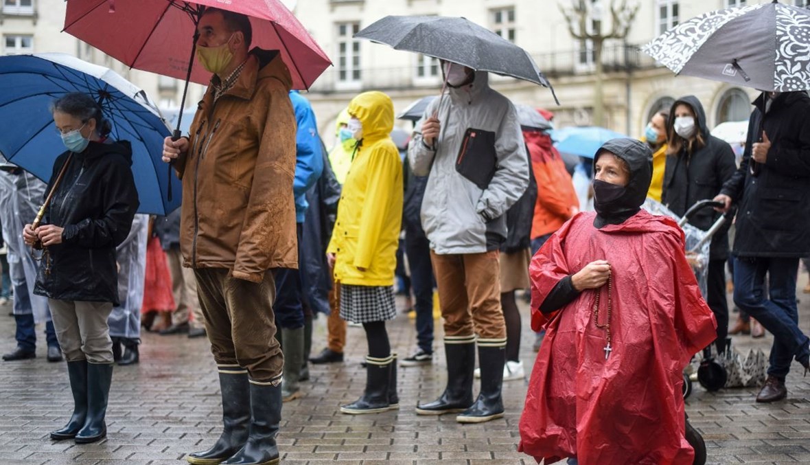 مسيحيون كاثوليك يصلون تحت المطر خلال تجمع في نانت للمطالبة بإعادة فتح أماكن العبادة خلال الإغلاق الوطني في فرنسا (15 ت2 2020، ا ف ب). 