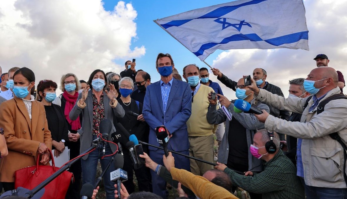 بورغسدورف خلال محاولته الادلاء بتصريح، بينما هتف متظاهرون إسرائيليون على مقربة منه ورفعوا أعلاما إسرائيلية في موقع جفعات هماتوس في القدس الشرقية (16 ت2 2020، أ ف ب). 