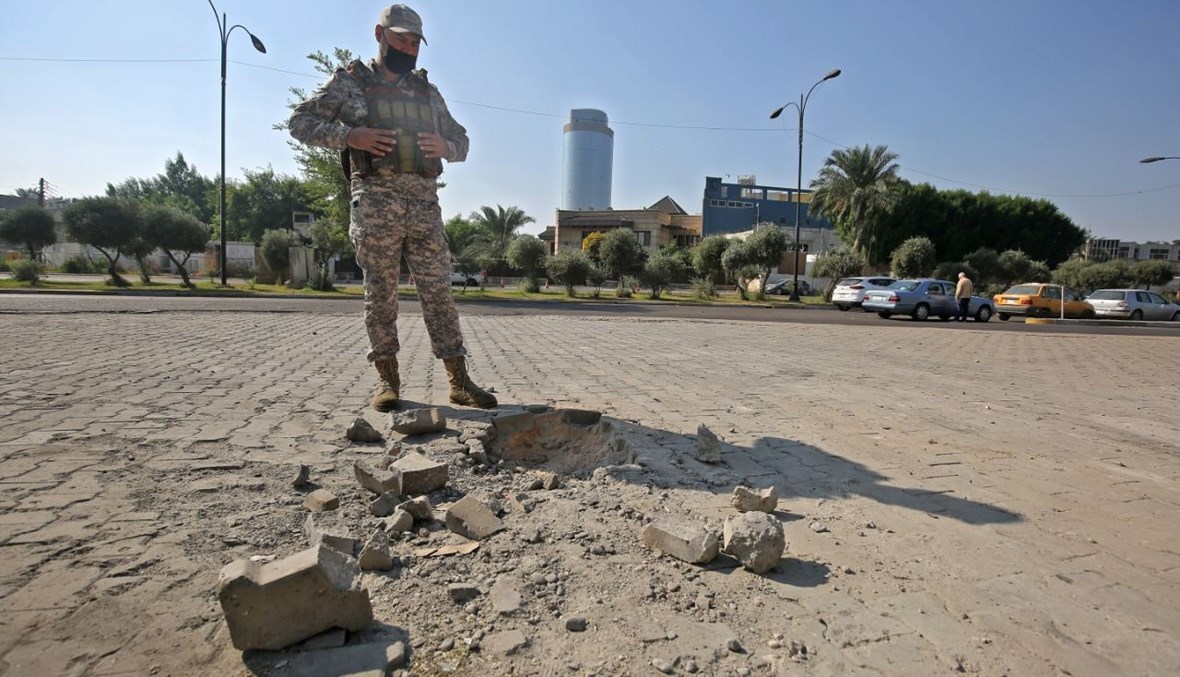عنصر من قوات الأمن العراقية يتفقد الأضرار خارج حديقة الزوراء في العاصمة بغداد بعد سقوط صواريخ (18 ت2 2020، أ ف ب). 