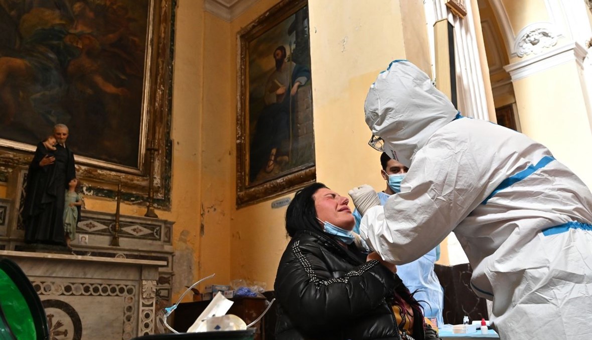 عامل صحي يأخذ مسحة أنفية من امرأة خلال حملة اختبار سريع لكورونا في نابولي (23 ت2 2020، أ ف ب). 
