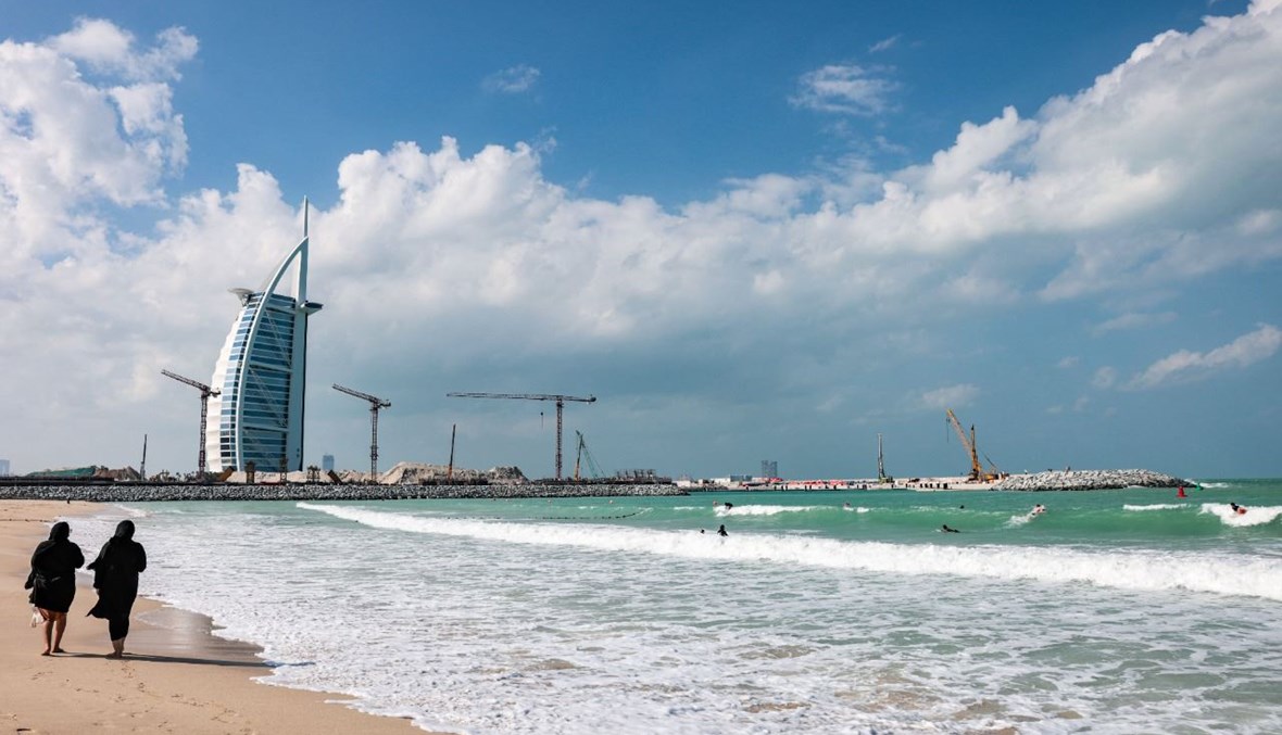 امرأتان تشميان على الشاطئ بالقرب من فندق برج العرب في دبي  (24 ت2 2020، أ ف  ب).