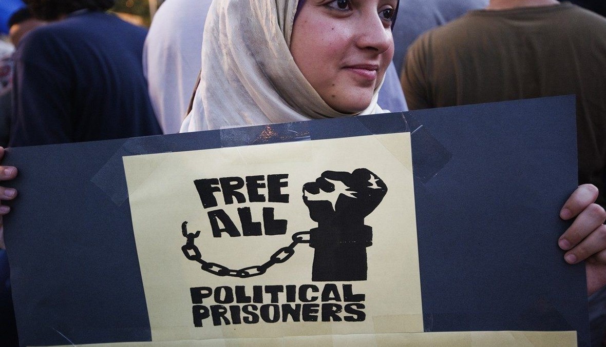 متظاهرة في مصر تحمل لافتة تدعو لتحرير الموقوفين السياسيين (أ ف ب).