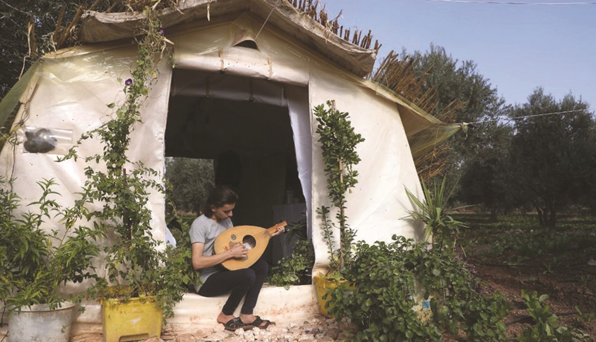 وسام دياب يعزف على العود أمام خيمته.(أ ف ب)