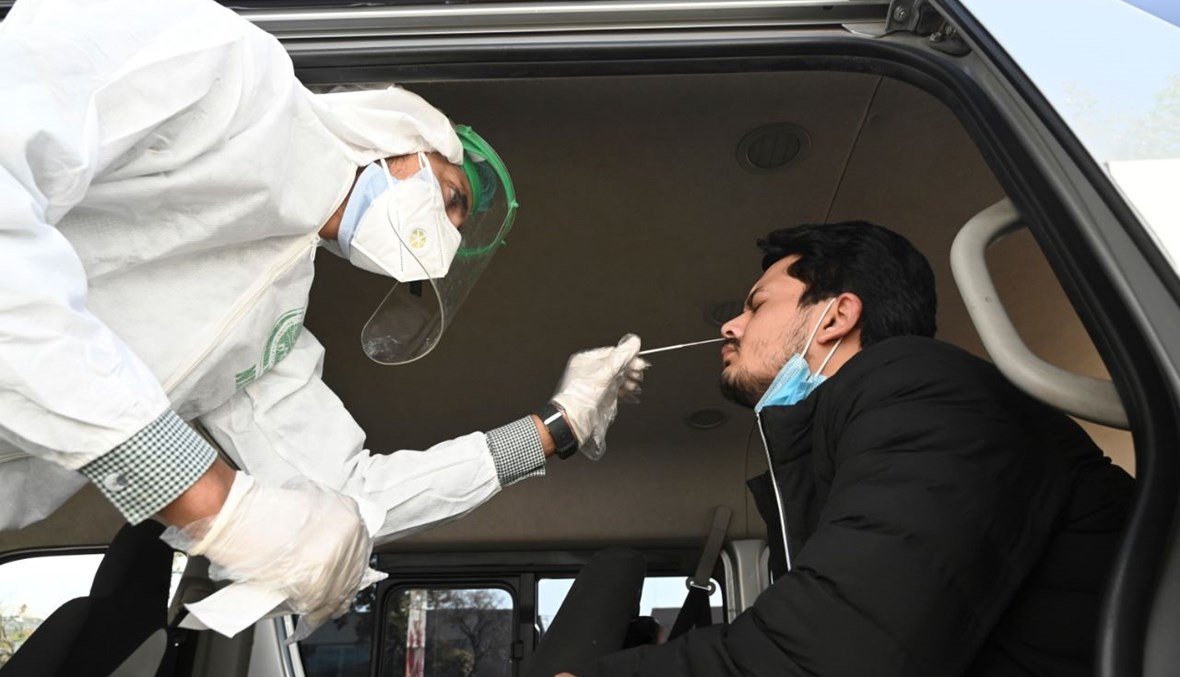 عامل صحي يأخذ مسحة انفية من رجل داخل شاحنة على جانب الطريق في إسلام أباد (26 ت2 2020، أ ف ب). 