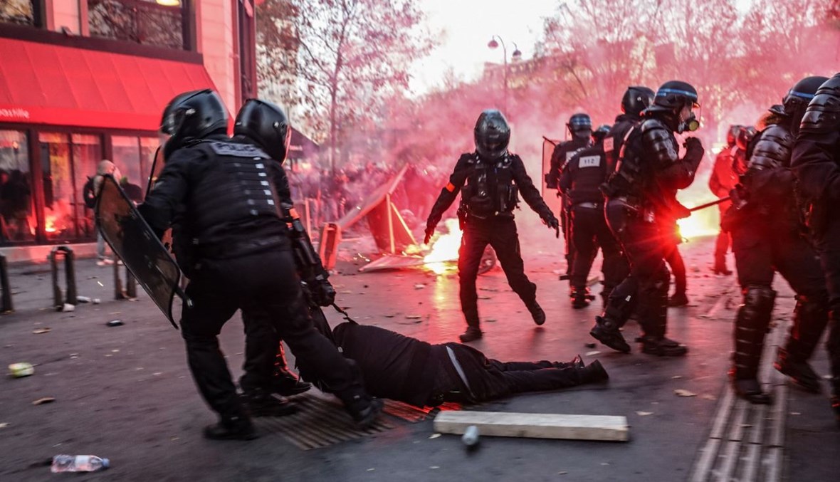 شرطيون يجرون رجلاً على الأرض في باريس، خلال احتجاج على مشروع قانون "الأمن الشامل" (28 ت2 2020، أ ف ب). 