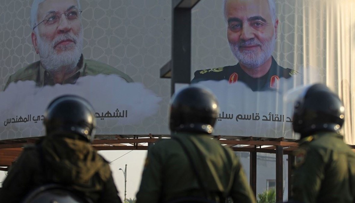 عناصر من الشرطة العراقية أمام صورتين لقائد لقاسم سليماني - الى اليمين - وأبو مهدي المهندس في أحد ساحات بغداد أمس.(أ ف ب)