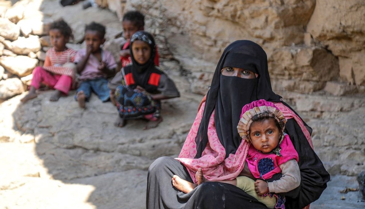 امرأة تحمل طفلاً أمام كهف لجأت إليه أسرة يمنية بسبب الفقر ونقص السكن، غرب ضواحي مدينة تعز اليمنية (2 ك1 2020، أ ف ب). 