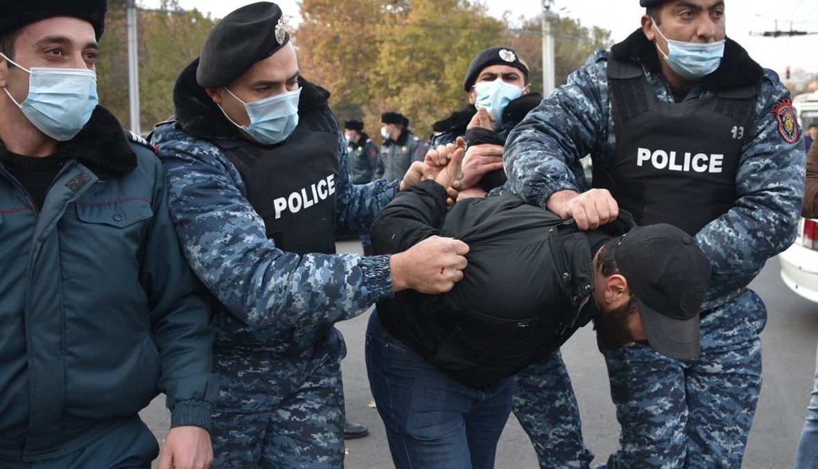 شرطيون يحتجزون متظاهرا خلال مسيرة مناهضة لباشينيان في يريفان (11 ك1 2020، أ ف ب). 