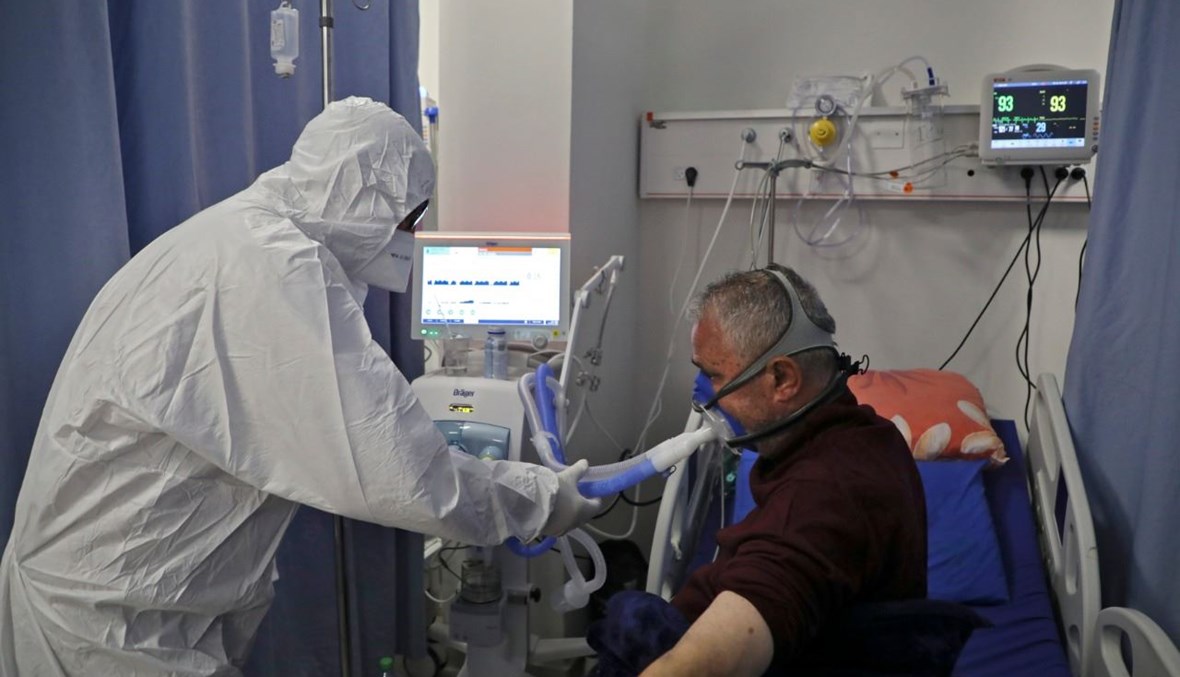 ممرض فلسطيني يعتني بمريض في مستشفى الدورة العام في مدينة الخليل بالضفة، حيث يعالج مرضى كورونا (18 ك1 2020، أ ف ب).