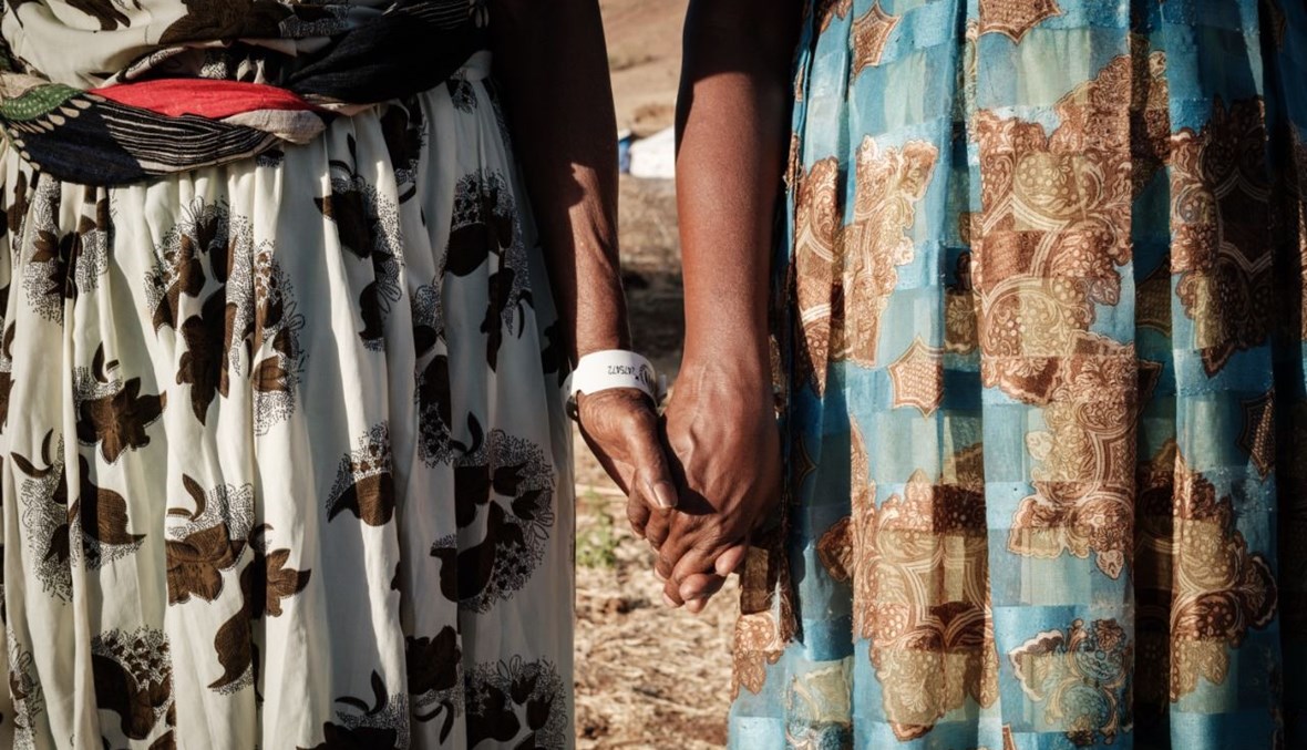 الإثيوبية أسافو الأمايا (إلى اليسار)، وهي مسنة كفيفة، تمسك ابنتها  بيدها في مخيم أم الراقوبة في ولاية القضارف شرق السودان (12 ك1 2020، أ ف ب). 