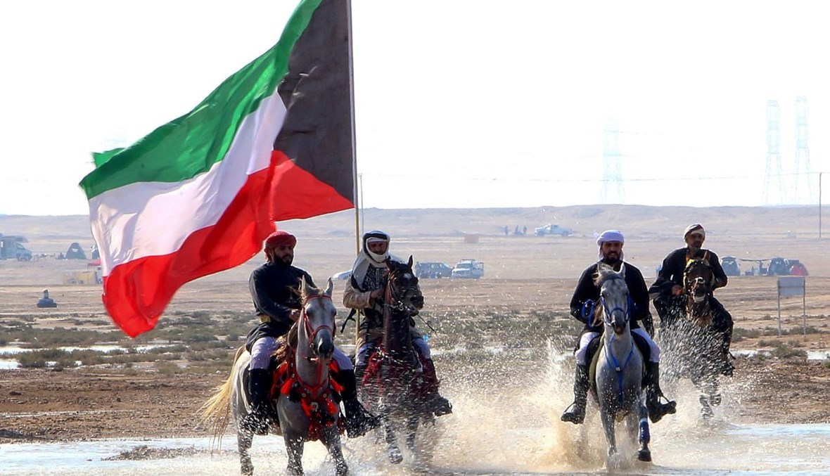 أعضاء من فريق الفرسان الكويتيين يحملون العلم الكويتي خلال أداء مع خيولهم على الشاطئ غرب العاصمة الكويت (11 ك1 2020، أ ف ب). 