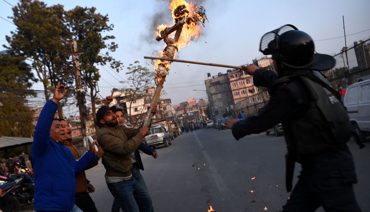 شرطي يحاول منع متظاهرين من اتحاد الطلاب النيباليين من حرق دمية تمثل رئيس الوزراء خلال تظاهرة في كاتماندو بعد حل البرلمان (20 ك1 2020، أ ف ب). 