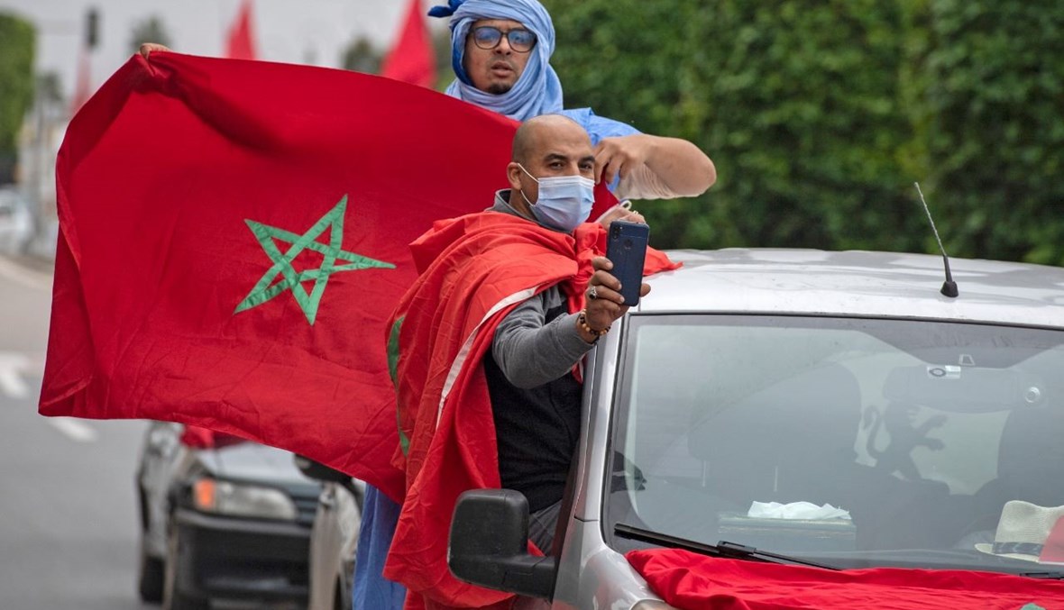 مغاربة يحتفلون أمام مبنى البرلمان بالرباط بعدما تبنت الولايات المتحدة خريطة رسمية جديدة للمغرب تشمل إقليم الصحراء الغربية المتنازع عليه (13 ك1 2020، أ ف ب). 