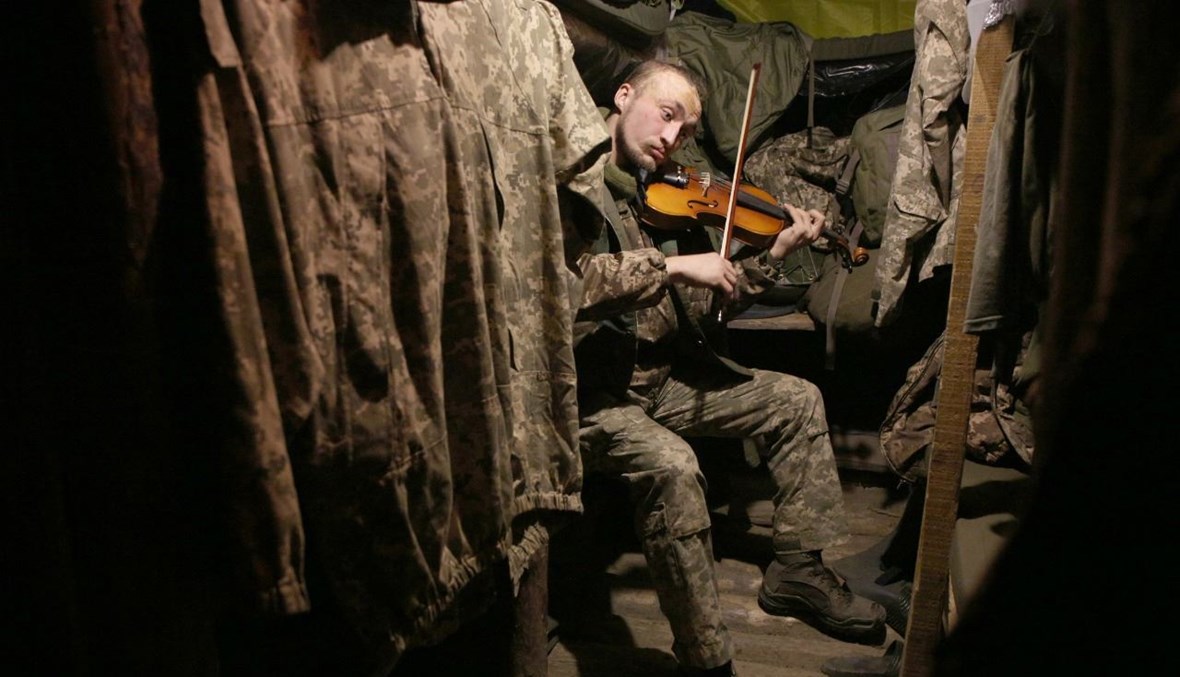 جندي أوكراني يعزف على الكمان في موقع على خط المواجهة مع الانفصاليين المدعومين من روسيا، على مقربة من غورليفكا، في منطقة دونيتسك (22 ك1 2020، أ ف ب).