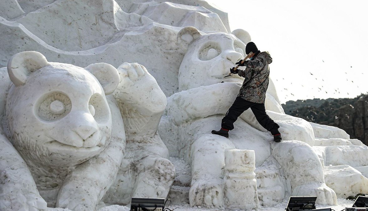 رجل ينحت تمثالاً ثلجياً لباندا في منطقة شنيانغ في مقاطعة لياونينغ الصينية بعد تساقط الثلوج في 26 كانون الأول 2020.
