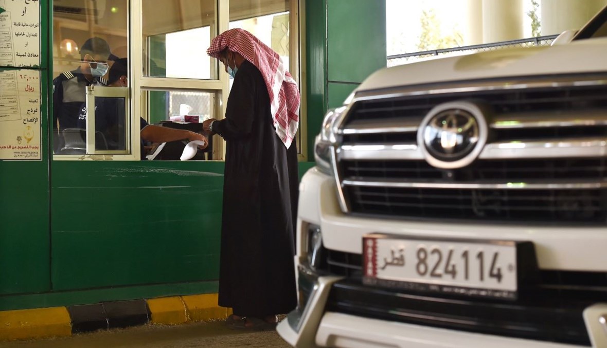 رجل يبرز وثائقه لمسؤول جمركي سعودي عند معبر سلوى الحدودي، قبل دخول السعودية (10 ك2 2021، أ ف ب).