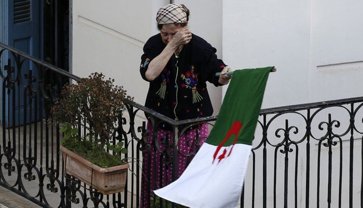 امرأة تمسح دموعها وهي تحمل العلم الجزائري لدى خروج المتظاهرين إلى الشوارع في العاصمة الجزائر، رفضا للانتخابات الرئاسية ( 27 ك1 2019، أ ب). 