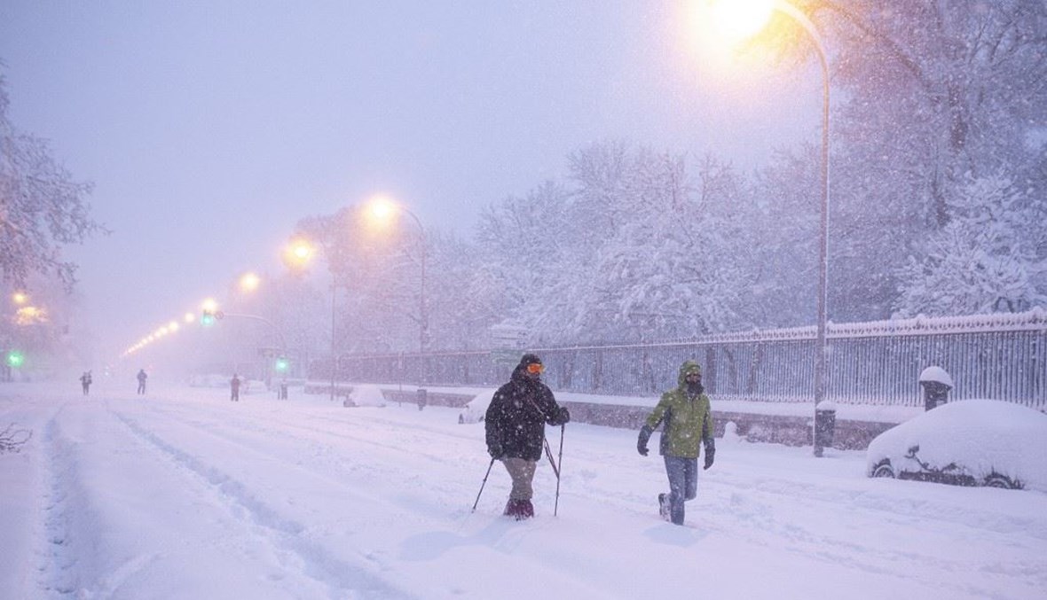 أشخاص يسيرون وسط الثلوج في مدريد السبت.   (أ ف ب)