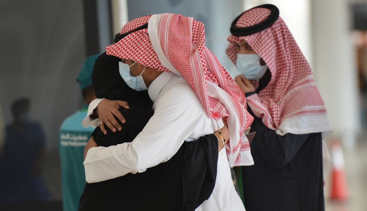 رجل يعانق أخته لدى وصولها الى مطار الملك خالد الدولي في الرياض، آتية في أول رحلة تجارية من قطر (11 ك2 2021، أ ف ب). 
