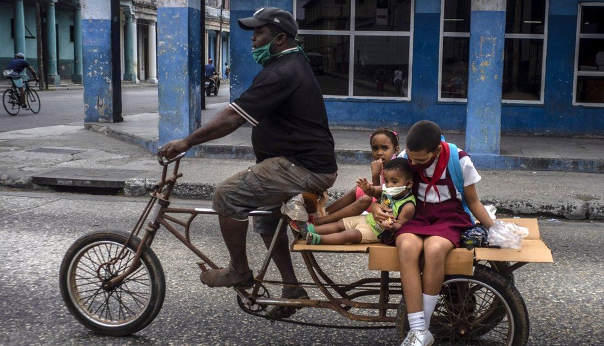 رجل ينقل اطفالا على دراجة ثلاثية العجلات في هافانا بكوبا (8 ك2 2021، أ ب). 