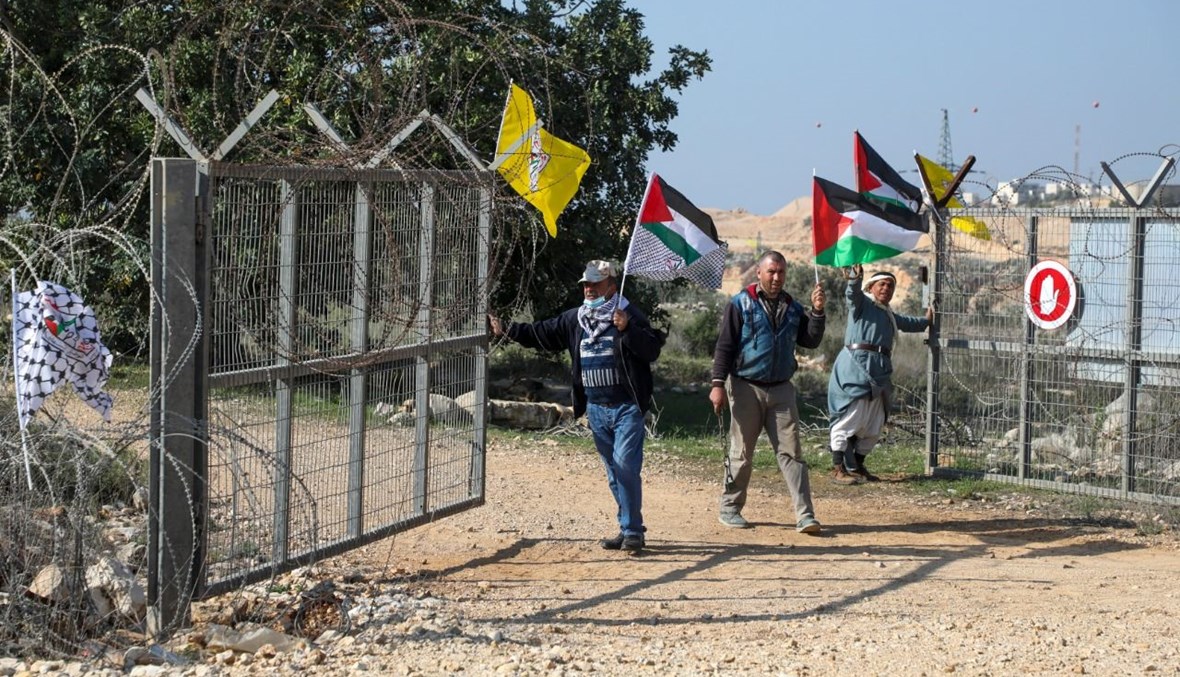 متظاهرون فلسطينيون يفتحون بوابة، هي جزء من جدار إسرائيلي، في قرية كفر ثلث شرق قلقيلية بالضفة (9 ك2 2021، أ ف ب).
