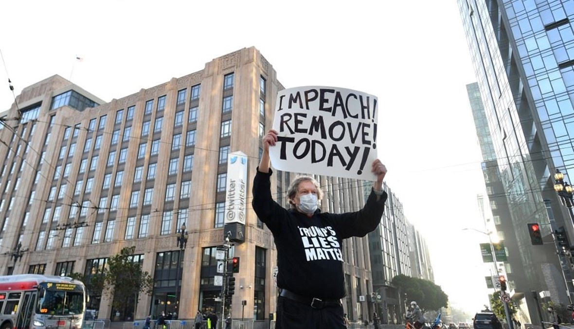 رجل يحمل لافتة تدعو إلى عزل الرئيس دونالد ترامب أمام مبنى شركة تويتر في سان فرانسيسكو بولاية كاليفورنيا الإثنين.   (أ ف ب)