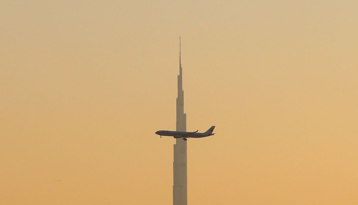 طائرة تجارية تحلق فوق برج خليفة لدى بدء هبوطها في مطار دبي الدولي في الإمارات (9 ك2 2021، أ ف ب).