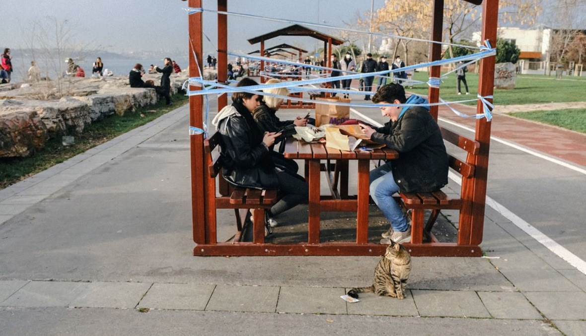 أشخاص يتناولون الطعام على مقاعد خارجية في كاديكوي في اسطنبول (11 ك2 2021، أ ف ب).