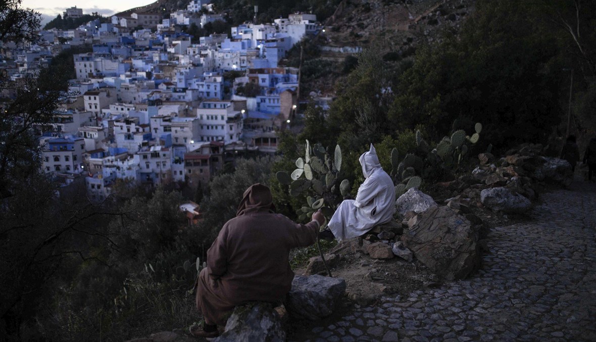رجلان جلسا على تلة تشرف على مدينة شفشاون المعروفة بلؤلؤة المغرب الزرقاء (أ ب). 