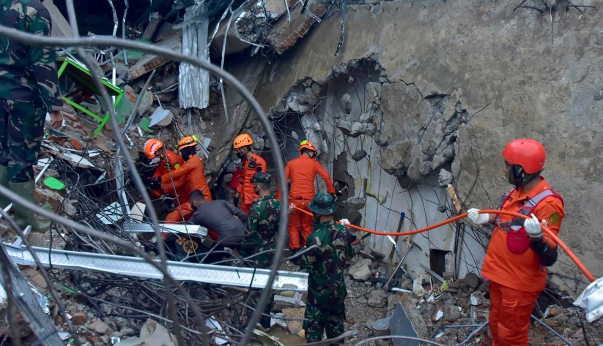 رجال إنقاذ يبحثون عن ناجين تحت انقاض مبنى منهار في ماموجو (15 ك2 2021، أ ف ب). 