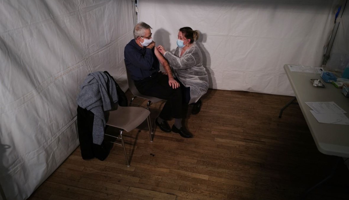 رجل مسن يتلقى حقنة من لقاح كورونا في مركز التطعيم في فوزول شرق فرنسا (18 ك2 2021، أ ف ب). 