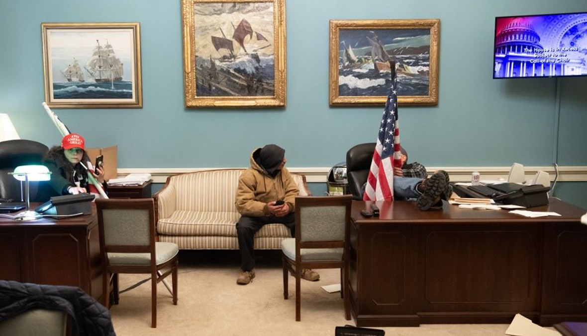 مؤيدون للرئيس الاميركي دونالد ترامب يجلسون في مكتب رئيس مجلس النواب الاميركي نانسي بيلوسي عقب اقتحام مبنى الكونغرس في 6 كانون الثاني الجاري.(أ ف ب)