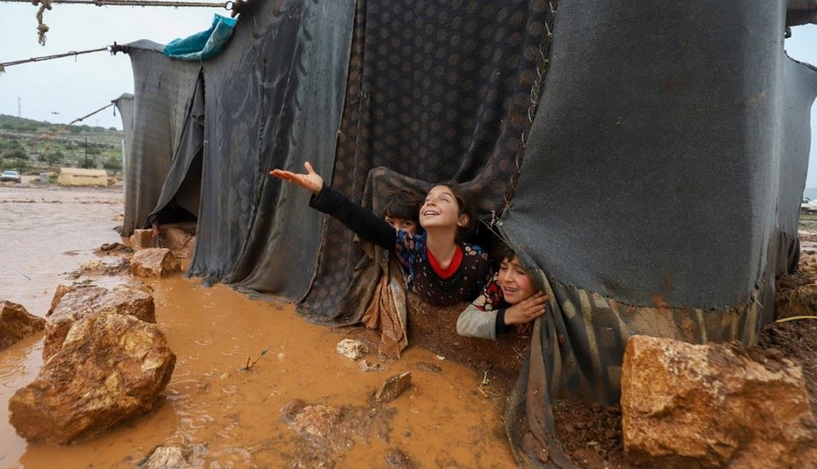 المياه تتدفق على خيمة للنازحين السوريين في مخيم أم جرن بمحافظة إدلب.   (أ ف ب)