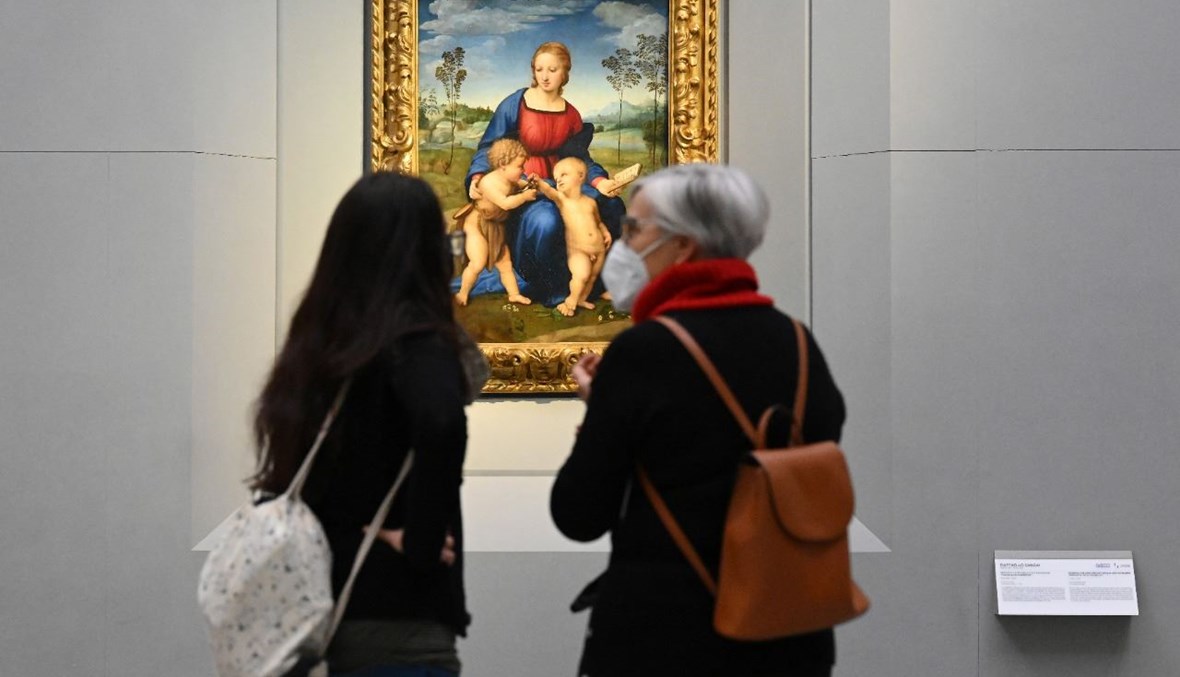 زوار وقفوا أمام لوحة لرافاييل في متحف "أوفيزي" في فلورنسا، بعد إعادة فتحه (21 ك2 2021، أ ف ب). 