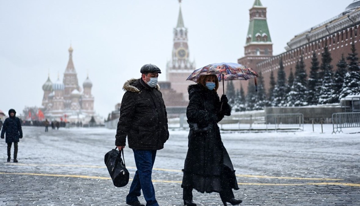 أشخاص يمشون في الساحة الحمراء خلال تساقط الثلوج في موسكو (21 ك2 2021، أ ف ب). 