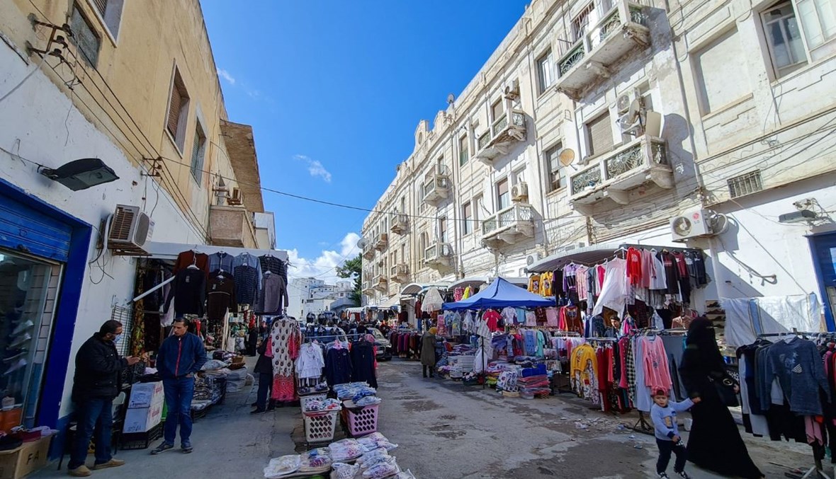 أصحاب متاجر ينتظرون الزبائن في سوق في المدينة القديمة في طرابلس (19 ك2 2021، أ ف ب).