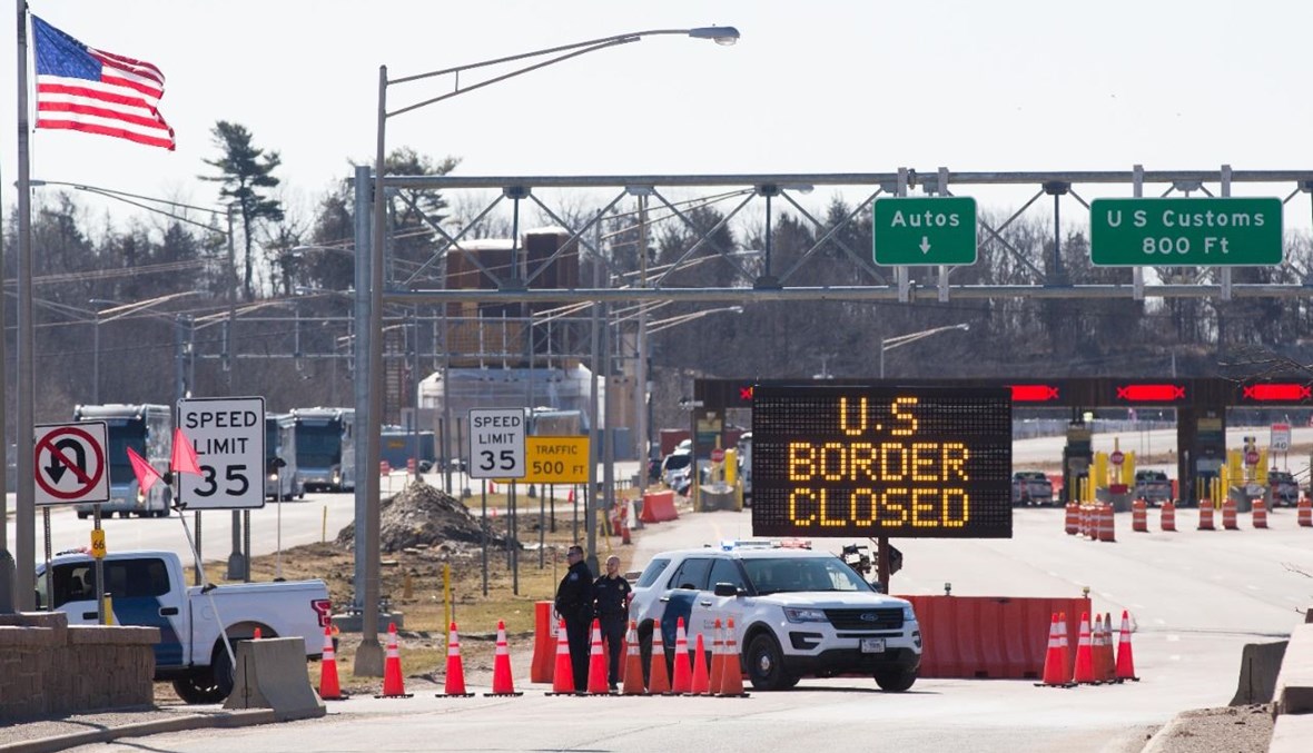صورة تعبيرية- ضباط جمارك أميركيون وقفوا بجانب لافتة تقول بأن الحدود الأميركية- الكندية مغلقة في لانسداون بأونتاريو (20 آذار 2020، أ ف ب). 