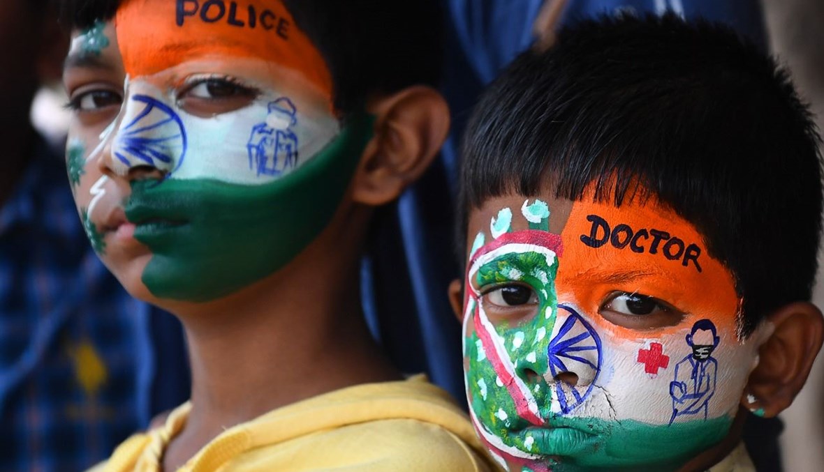 أطفال في مومباي لونوا وجوههم تكريماً للعاملين الصحيين الذين يكافحون كورونا، عشية الاحتفالات بيوم الجمهورية الهندية (24 ك2 2021، أ ف ب). 
