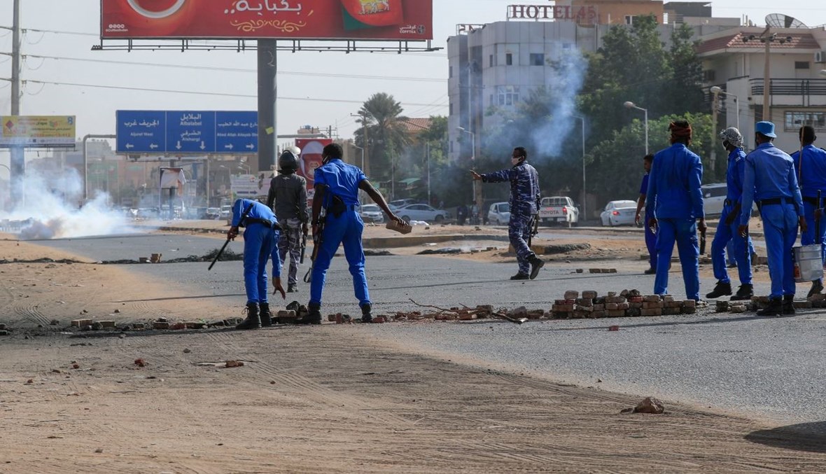 عناصر من قوات الأمن السودانية يزيلون حواجز وضعها متظاهرون في الخرطوم خلال احتجاج على الاوضاع الاقتصادية (24 ك2  2021، أ ف ب). 