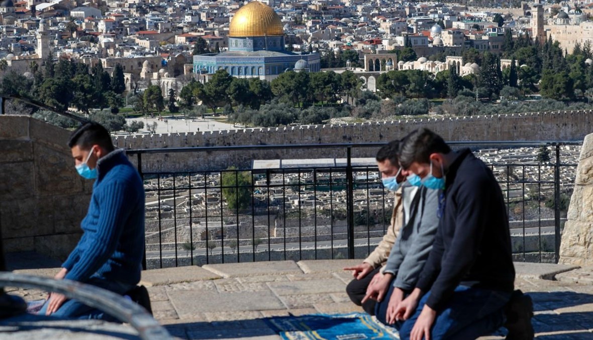 فلسطينيون يؤدون صلاة الجمعة في جبل الزيتون في القدس. وبدا المسجد الاقصى في الخلفية (22 ك2 2021، أ ف ب).