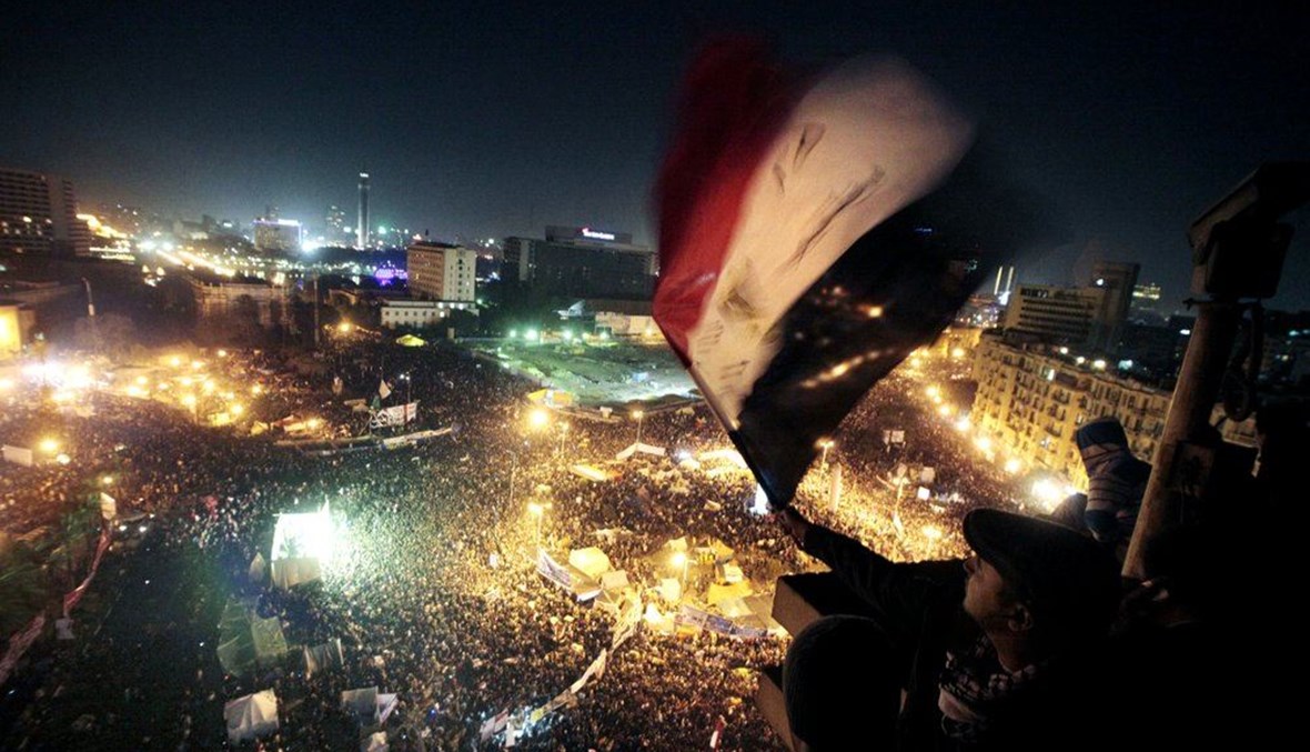 أشخاص يلوحون بالأعلام في ميدان التحرير في القاهرة في الذكرى الأولى للانتفاضة الشعبية في مصر (25 ك2 2012، أ ب). 