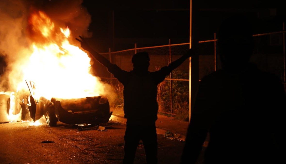 شبان يلتقطون الصور امام سيارة محترقة تردد انها تعود للقوى الامنية(مارك فياض)