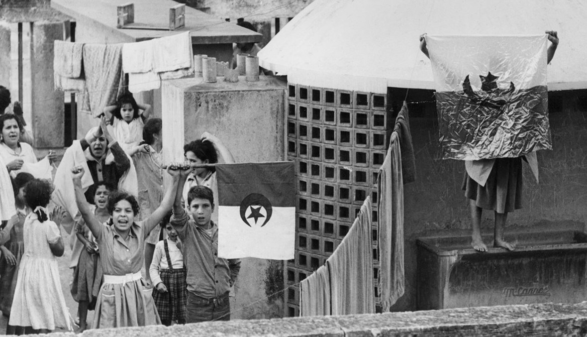 جزائريون يلوّحون بالعلم الوطني على سطح مبنى في الجزائر العاصمة، احتفالاً بعيد استقلال الجزائر (أرشيفية- أ ف ب / 1 تشرين الثاني 1961).