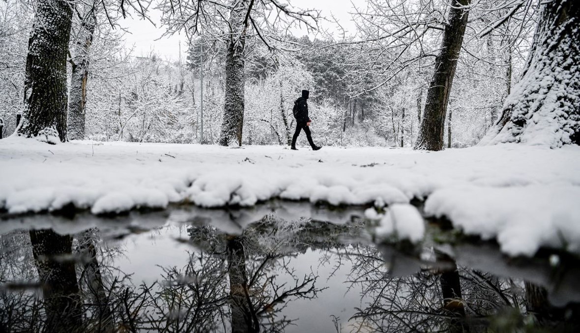 رجل يسير في حديقة مغطاة بالثلوج في بريشتينا (26 ك2 2021، أ ف ب). 