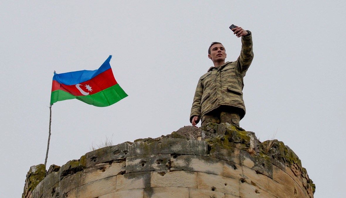 جندي أذربيجاني يلتقط صورة تذكارية بعد دخول كراباخ (أ ف ب).