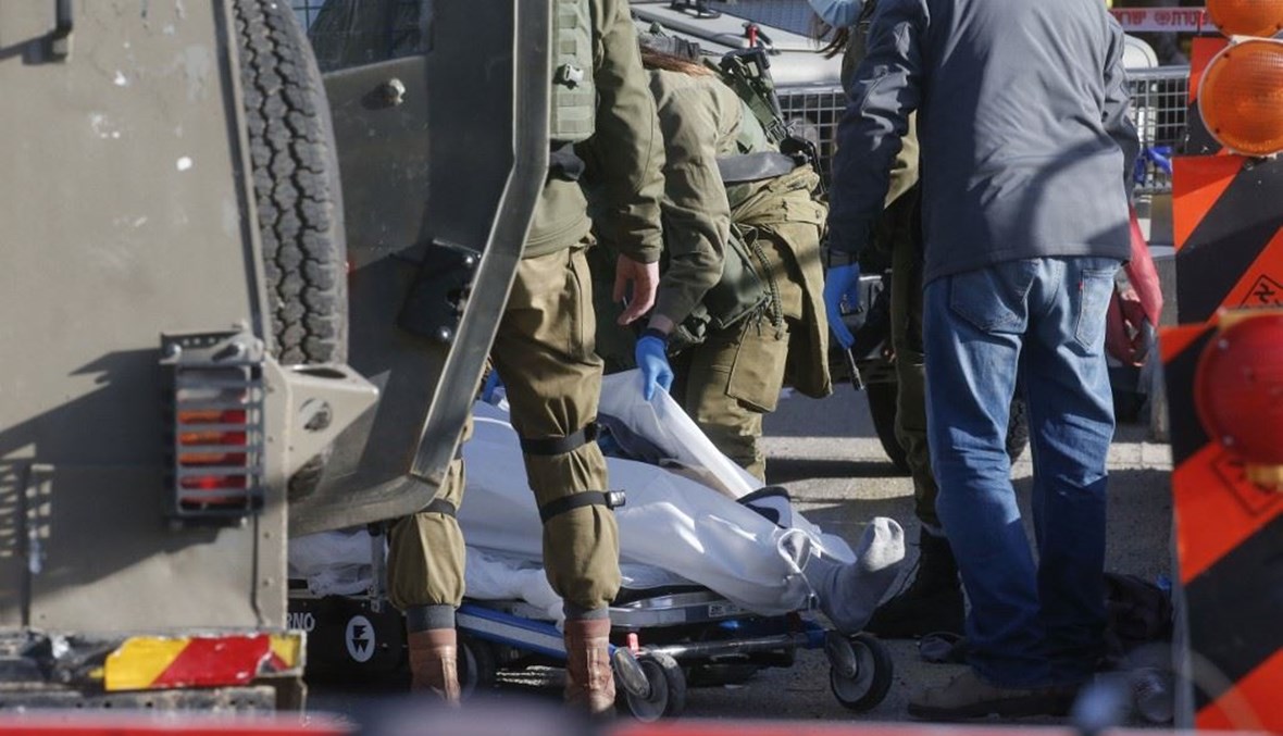 جنود اسرائيليون ينقلون جثى فلسطيني قتلوه بالرصاص قرب مستوطنة غوش عتصيون جنوب بيت لحم بالضفة الغربية أمس.    (أ ف ب)